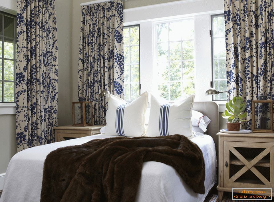 Plavo cvijeće na zavjesama i prugama na jastucima harmonično se kombinuje u unutrašnjosti spavaće sobe
