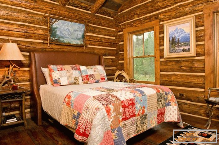 Spavaća soba u rustikalnom stilu u lovačkoj kući. Značajno ukrašavanje zidova pomoću log kuće. 
