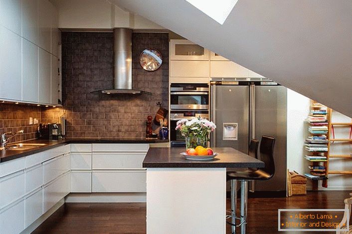 Kuhinja u potkrovlju je uređena u skandinavskom stilu. Bele kuhinjske garniture izgledaju dobro u pozadini zidova tamnih cigli. 