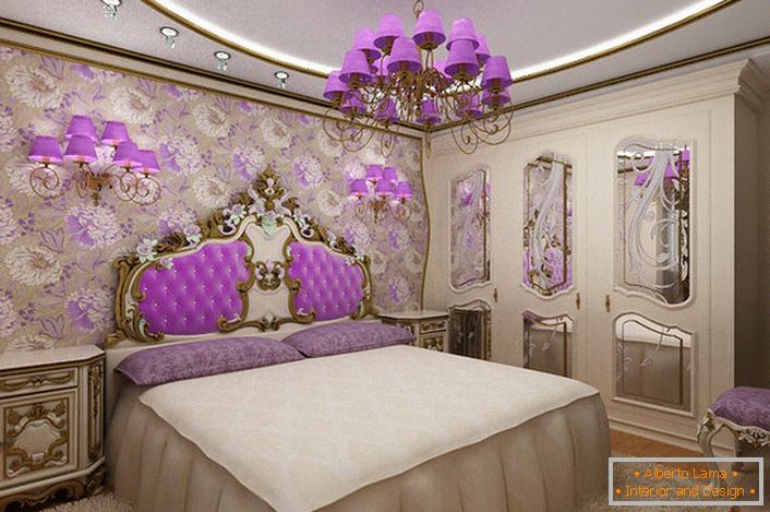 Elegantna barokna spavaća soba sa zanimljivim akcentom na osvetljenje. Lustre i noćne lampice sa istim ljubičastim nijansama harmonično u kombinaciji sa tapacirmom na leđima na glavi kreveta.