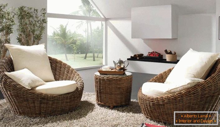 Wicker obimne fotelje sa belim mekim jastucima u kompletu sa tepihom sa visokim gomilom biće najbolja dekoracija sobe za goste u ekološkom stilu.
