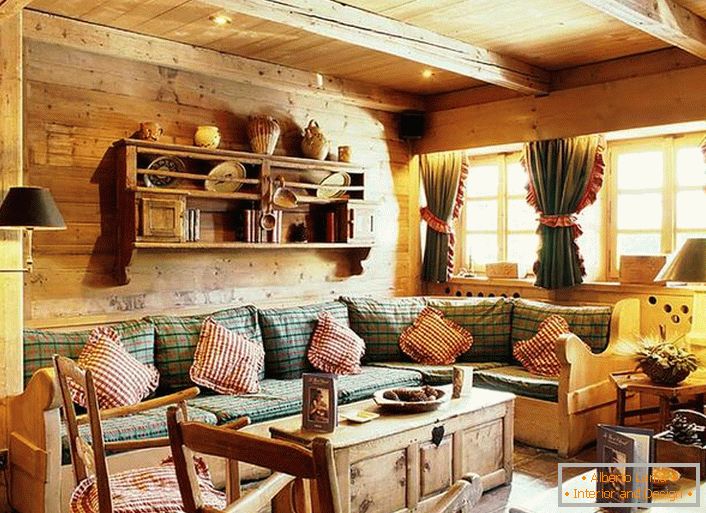 Drvena zidna dekoracija, kontrastni jastuci na mekanom sofu, guste zavese sa rupu na prozorima. Udoban dnevni boravak u rustikalnom stilu u seoskoj kući.