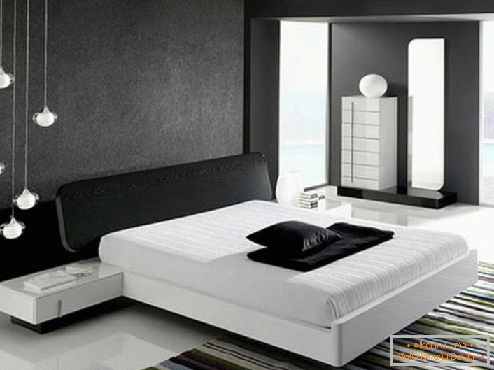 Zid na glavi kreveta, ukrašen sivim matim umetkom, u skladu sa stilom hi-tech je u saglasnosti sa sjajnim belim podom.