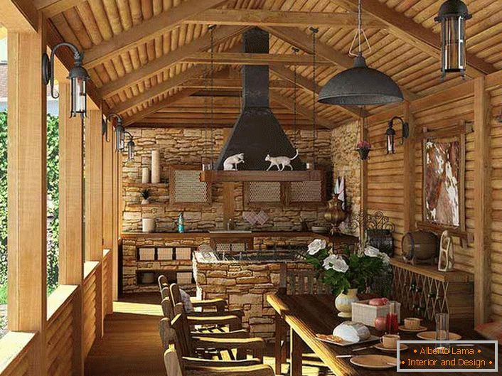 Mala kuhinja s roštiljem na verandi kuće. Stil stila je evidentiran, pre svega, dekoracijom zidova i plafona sa drvenim okvirom.