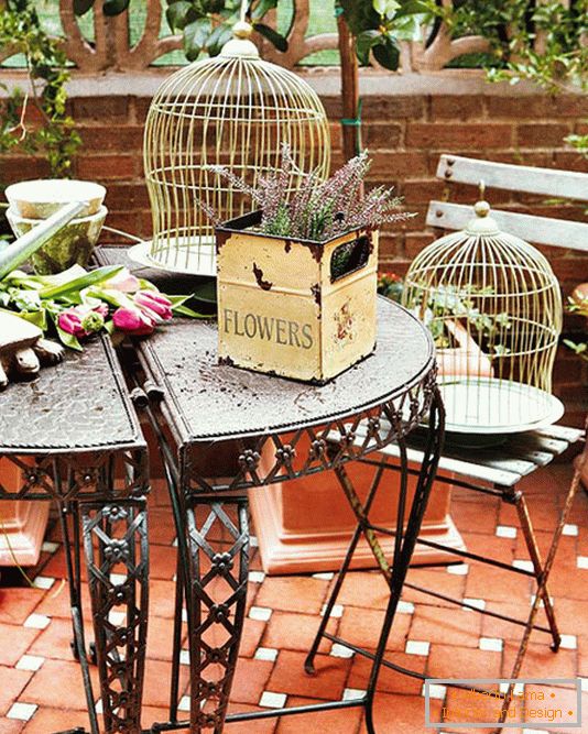 Kovani stol, kutije sa cvijećem i kavezom za ptice