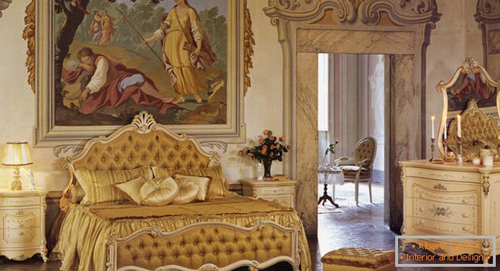 Spavaća soba u baroknom stilu u zlatnim bojama. Zid na glavi kreveta ukrašen je velikim starim slikama.