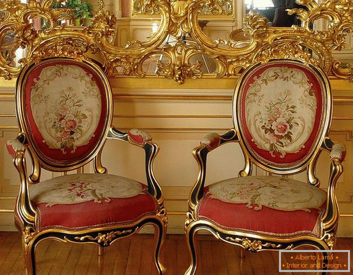 Otvoreni štukature zlatne boje na ogledalu i stolice sa crvenim mekim tapacirungom - svetli predstavnici baroknog stila.